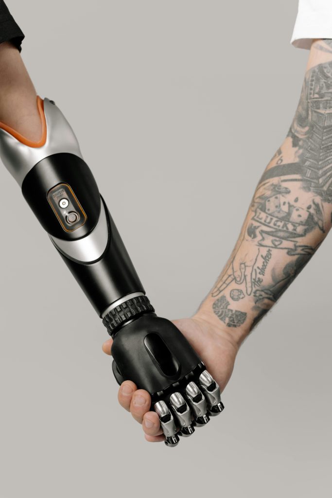 pexels-photo-6153346-6153346 A cybernetic prosthetic arm shakes hands with a tattooed arm, symbolizing unity.